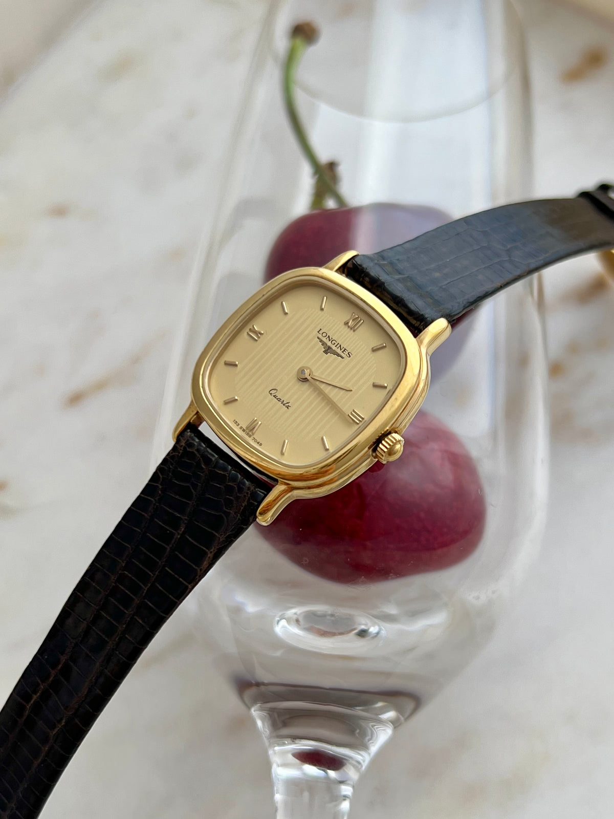 Longines Cushion Champagne Stripe Women’s Watch — Angled front view across a glass