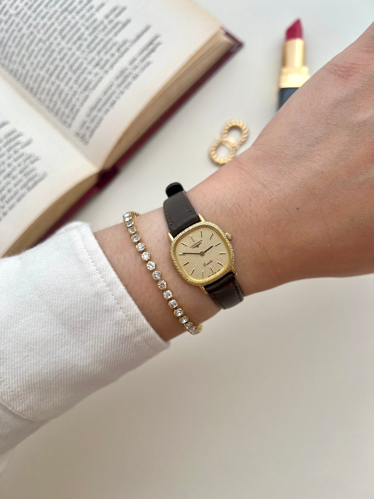 Angled view of the Longines gold cushion watch with engraved Florentine-style bezel and striped champagne dial.
