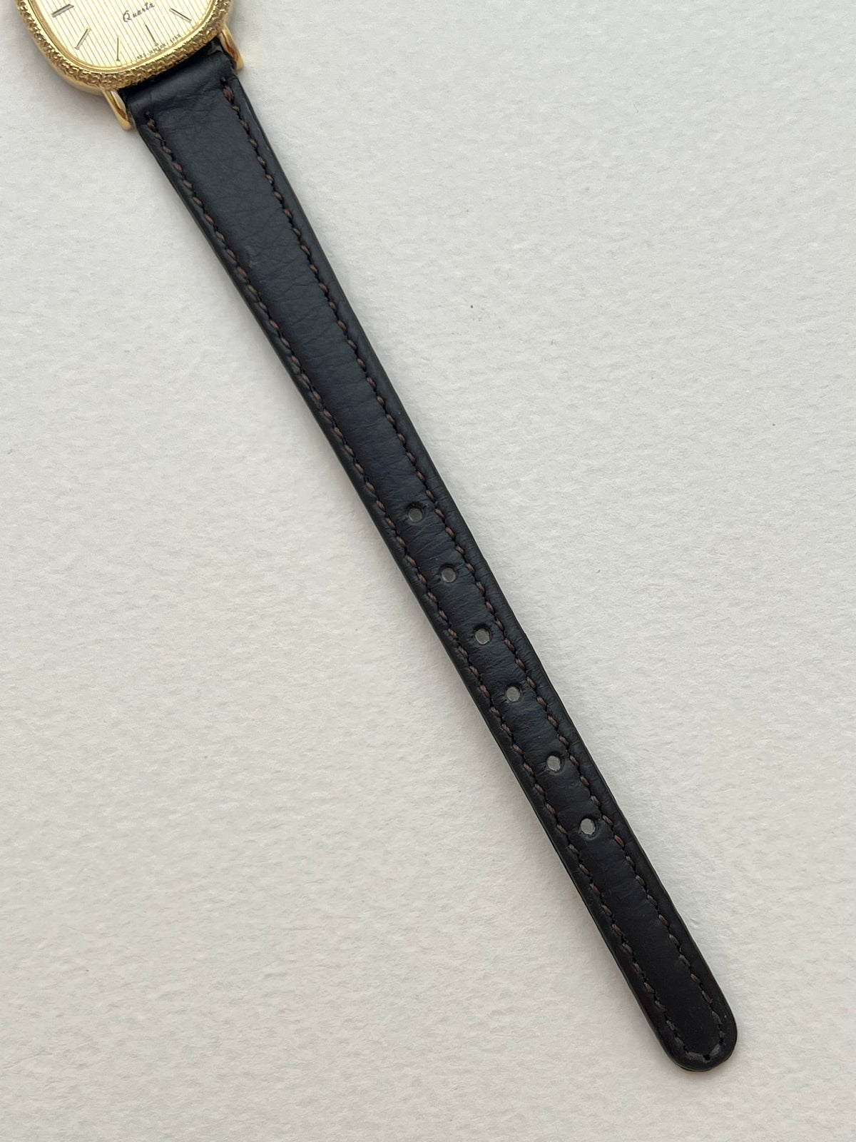 Side angle of the Longines gold cushion watch showing its engraved bezel and case.