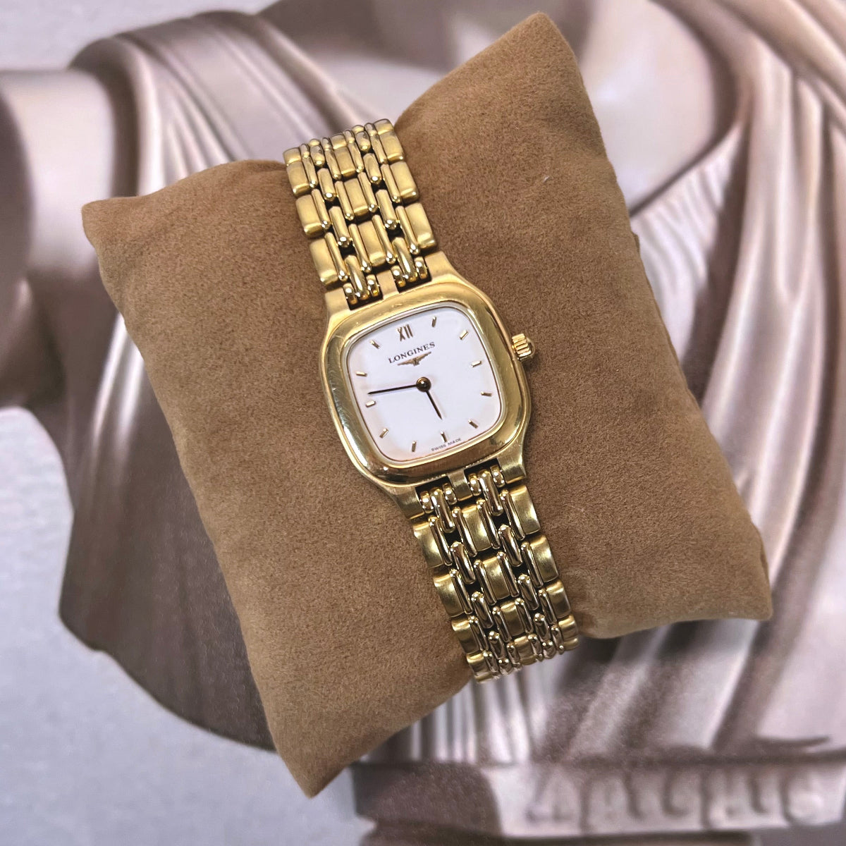 Longines women’s watch with draped gold tone link bracelet, white dial, Roman XII marker and softly cushioned square case.