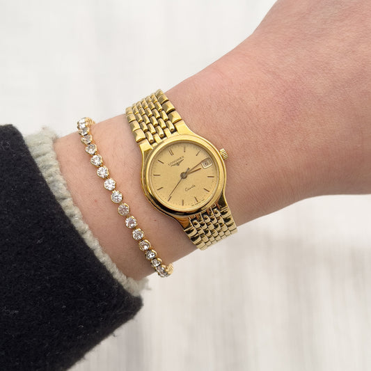 Longines gold-tone ladies watch with patterned champagne dial, date window and integrated bracelet.