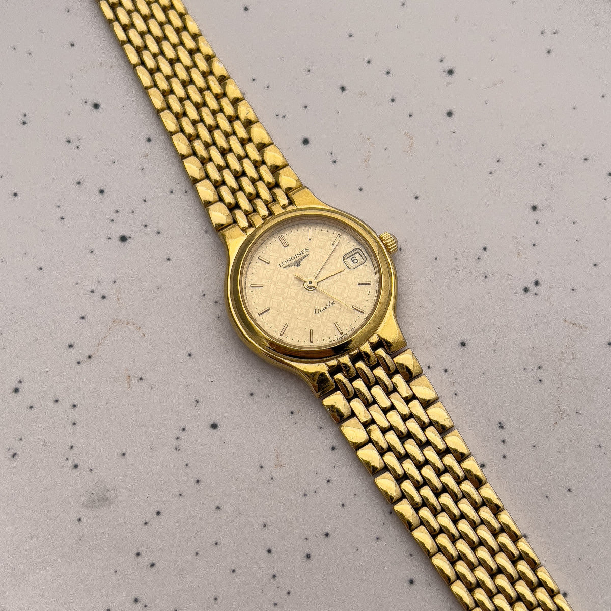 Longines watch with geometric dial motif and sculpted gold-tone bracelet.