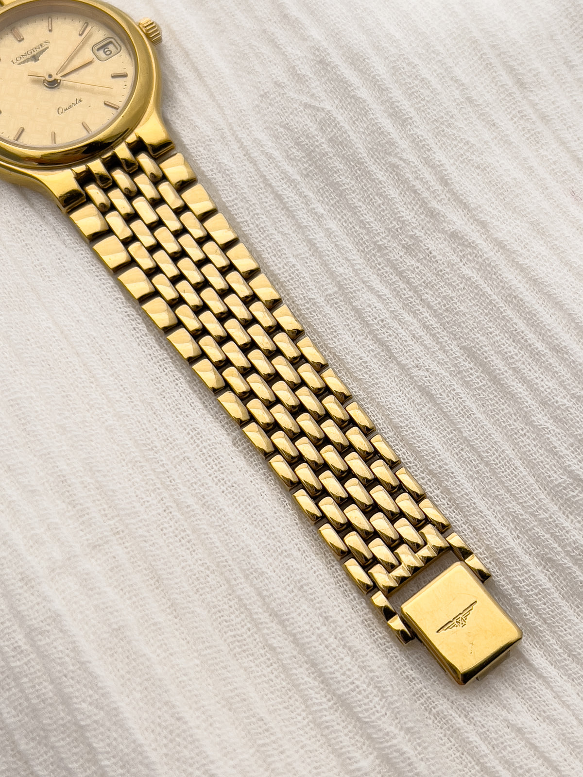 Classic Longines gold bracelet watch with round case and date window.