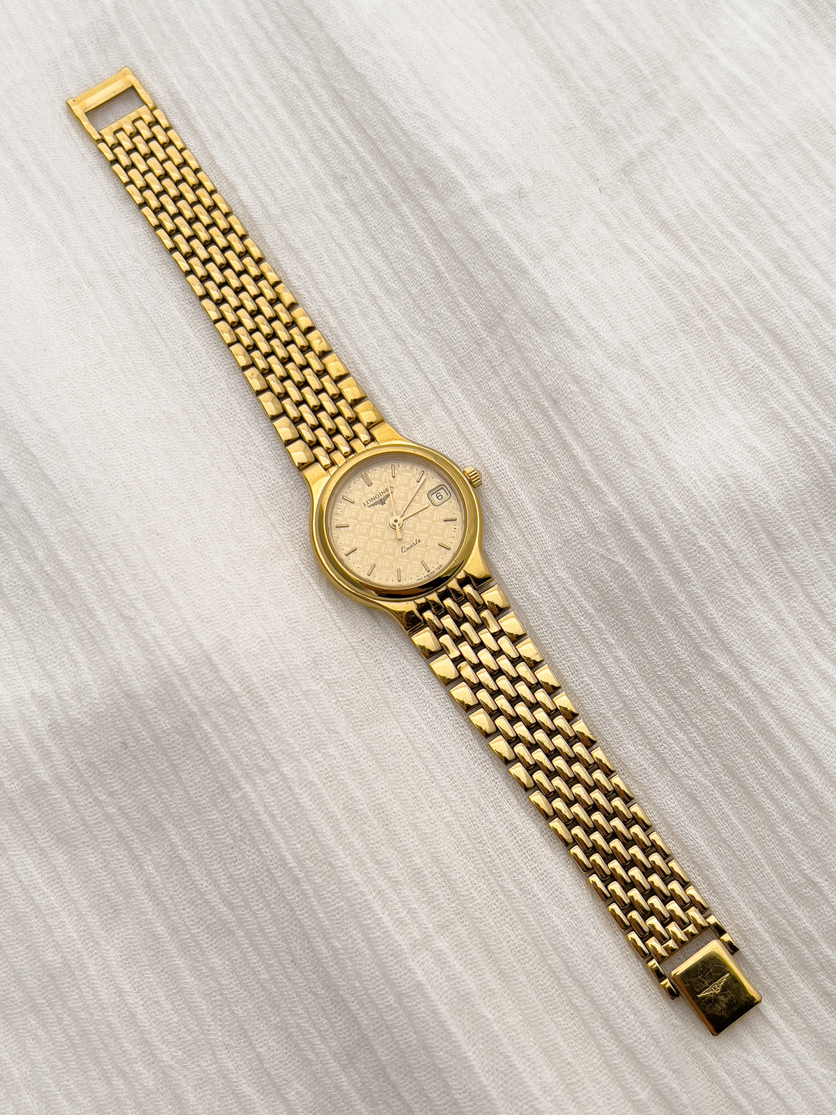 Vintage Longines watch with integrated gold bracelet and detailed champagne dial.