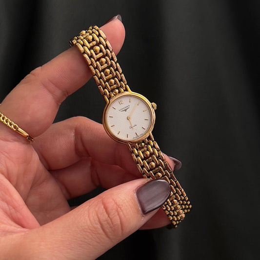 Longines gold-tone ladies watch with dotted champagne dial shown on a wrist.