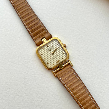 Longines gold square-cushion watch with honey-tan leather strap shown on a white background.