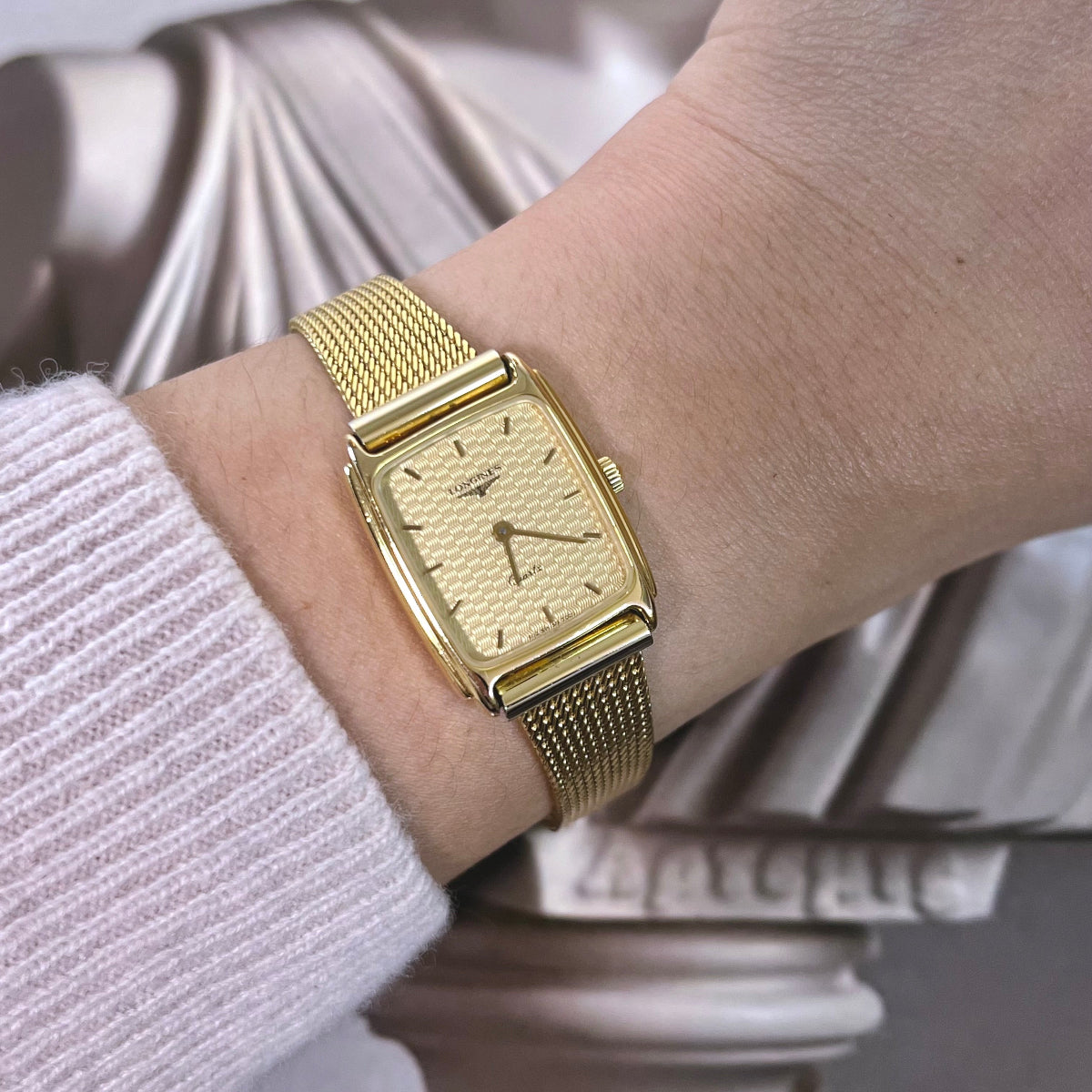Longines women’s watch with hologram like champagne patterned dial, gold tone rectangular case and fine mesh bracelet.