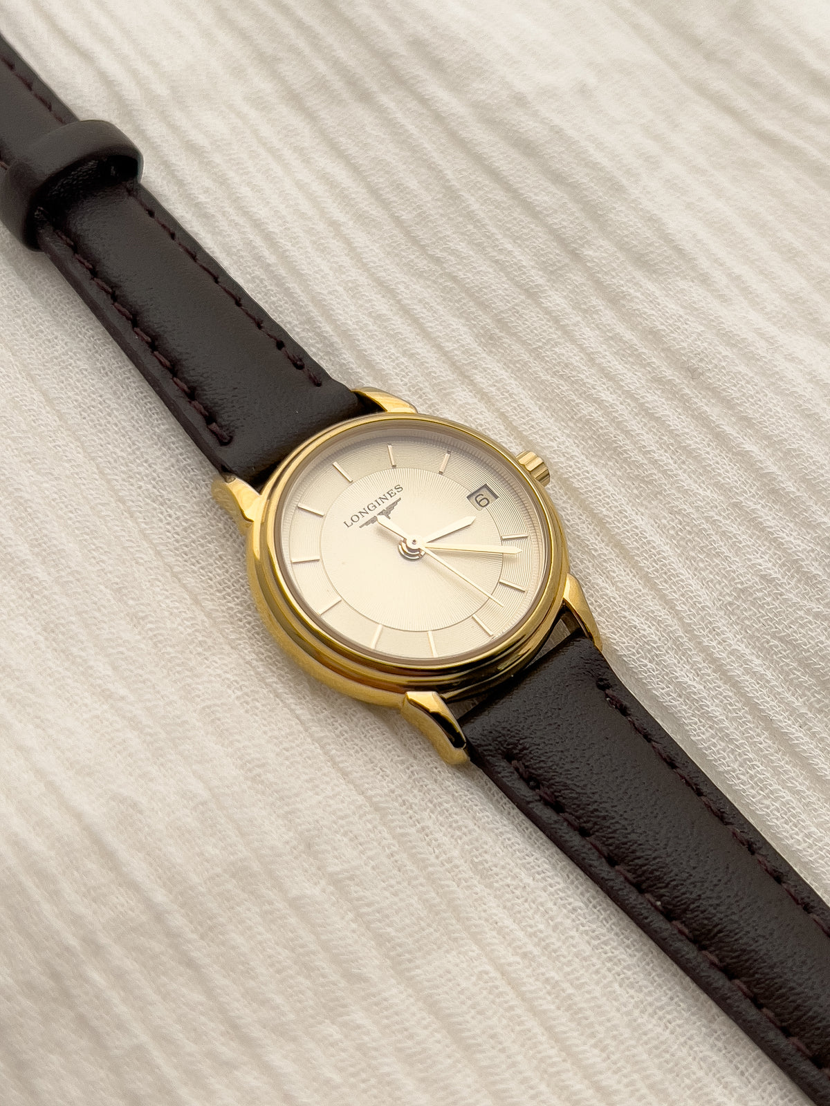 Angled view of the Longines gold-tone case and raised bezel.