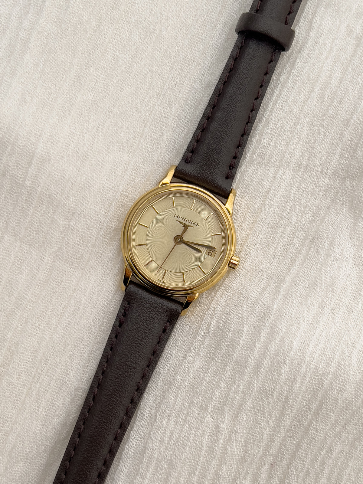 Longines gold-tone ladies watch with champagne dial and discreet date display.