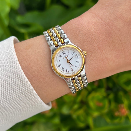 Longines La Grande Classique two tone women’s watch worn on wrist, white Roman numeral dial, date display and gold tone bezel