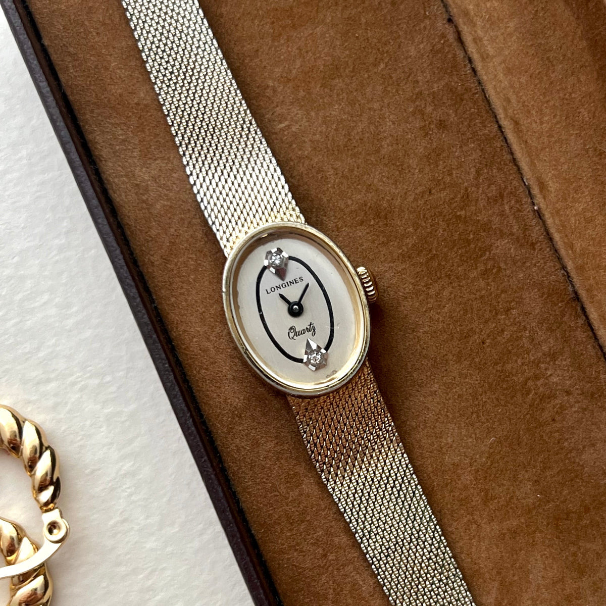 Close-up of the Longines ivory oval dial and two crystal accents at 12 and 6.