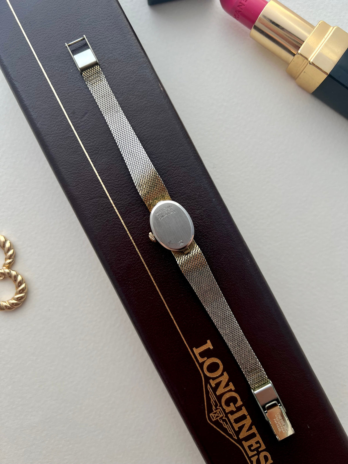 Longines oval watch photographed with a display box used as a styling prop; box is not included.