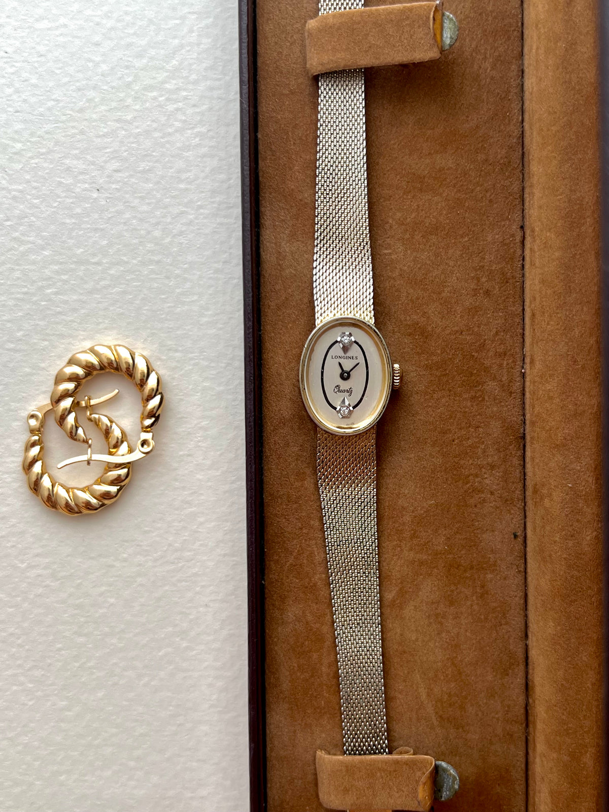 Angled view of the Longines oval gold-tone case and woven Milanese bracelet.