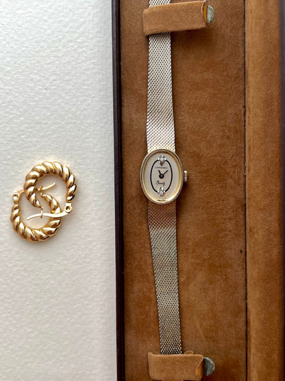 Angled view of the Longines oval gold-tone case and woven Milanese bracelet.