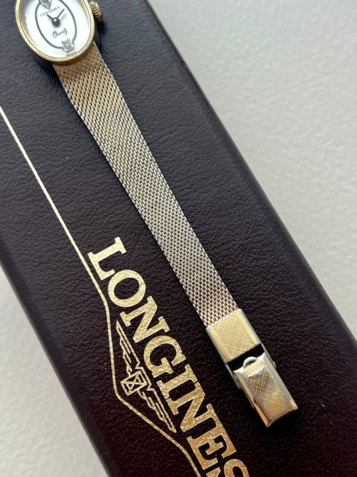 Close-up of the fluid woven gold-tone Milanese bracelet on the Longines watch.