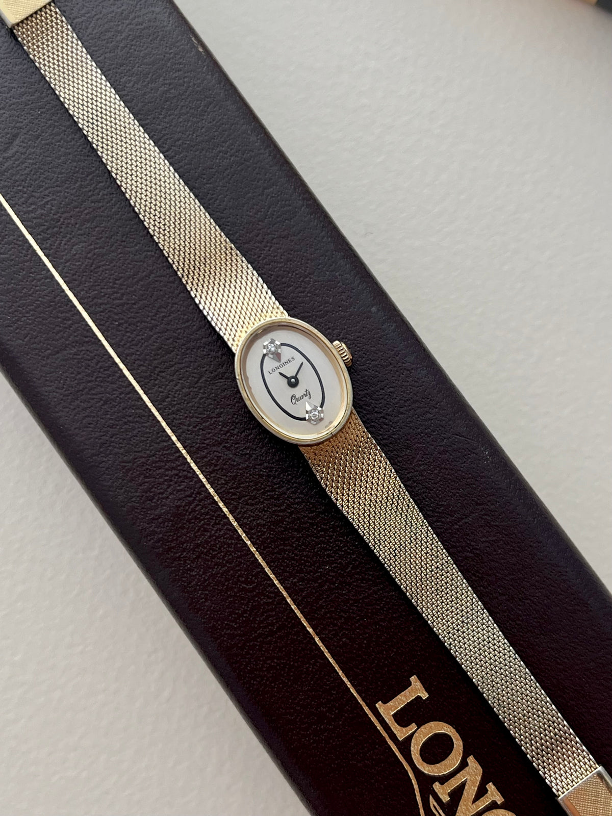 Side profile of the Longines oval gold-plated watch case and signed crown.