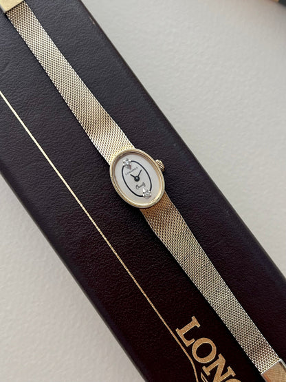 Side profile of the Longines oval gold-plated watch case and signed crown.