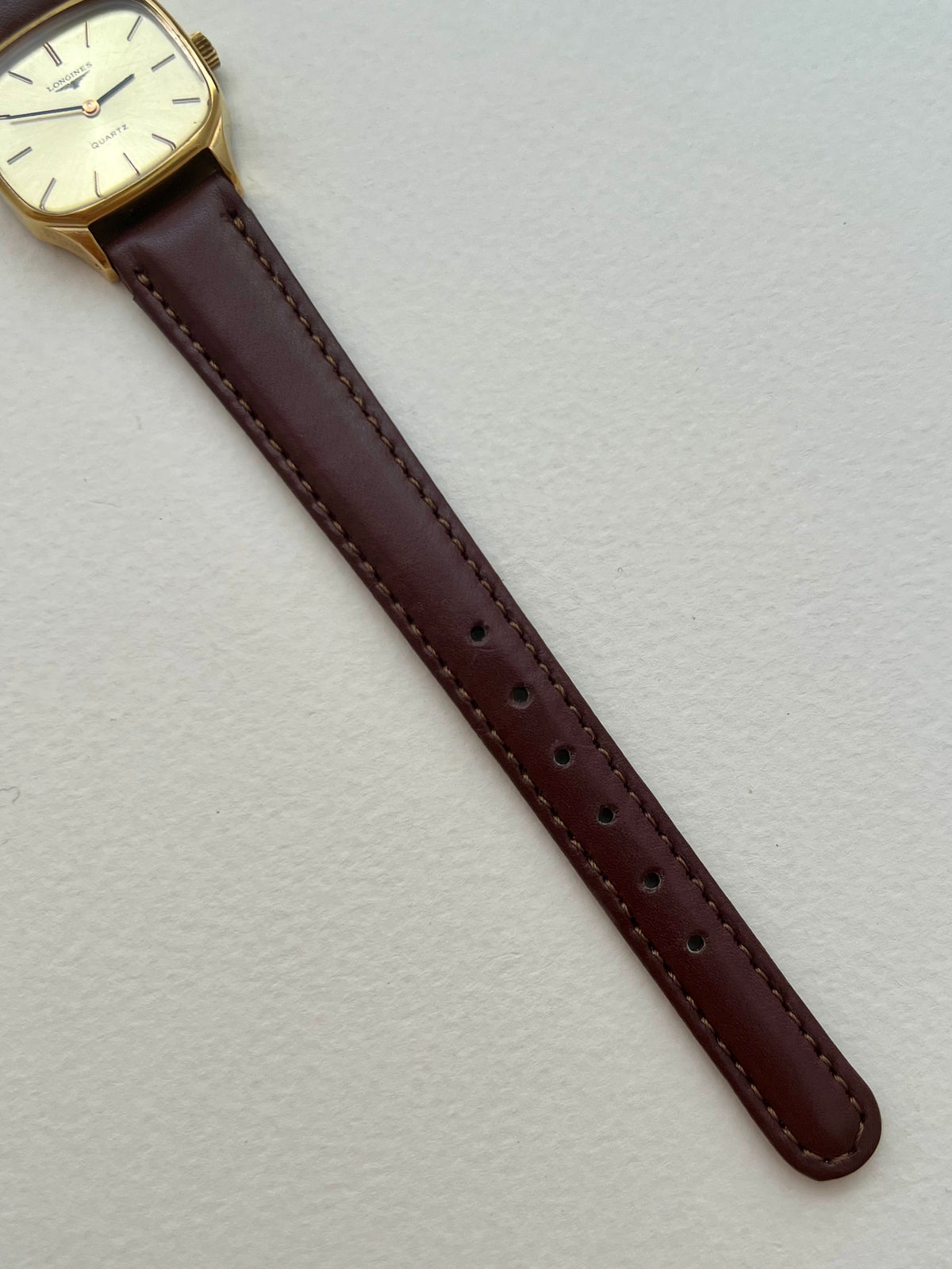 Detailed view of the Longines pale champagne dial with polished baton markers and black hands.