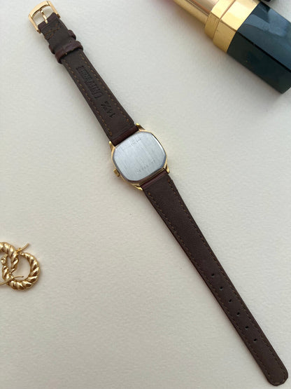 Side angle showing the curved soft-octagonal gold-tone case of the Longines watch.