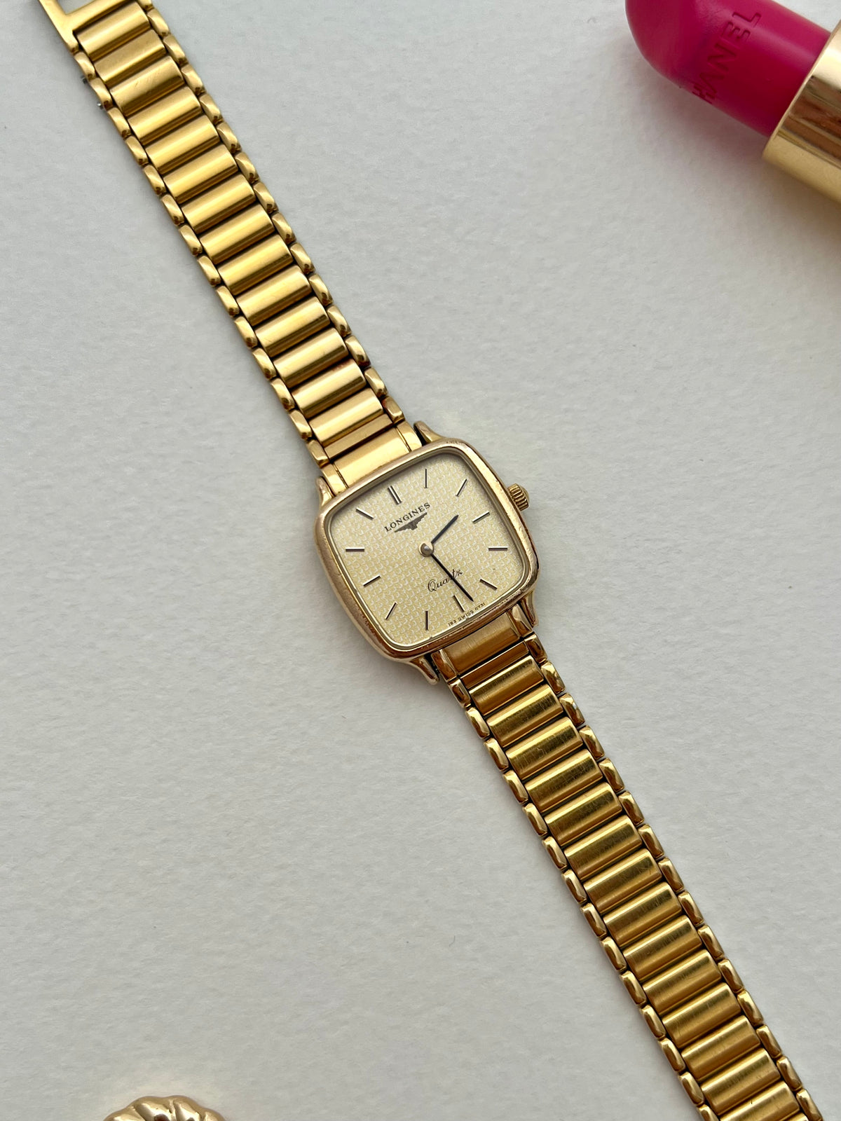 Angled view of the Longines soft-square gold-tone case and textured champagne dial.
