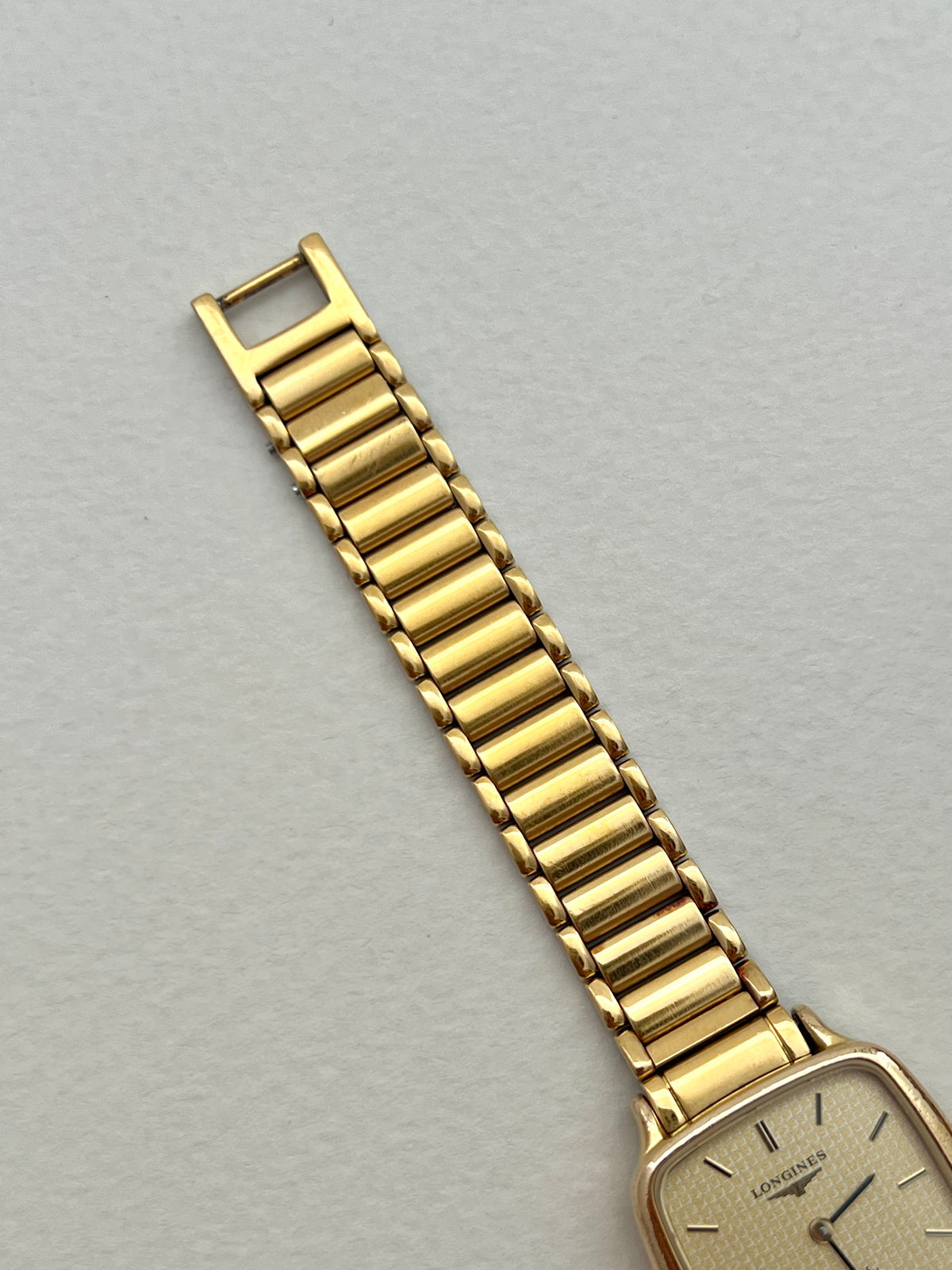 Side profile of the Longines soft-square gold-tone watch case and crown.