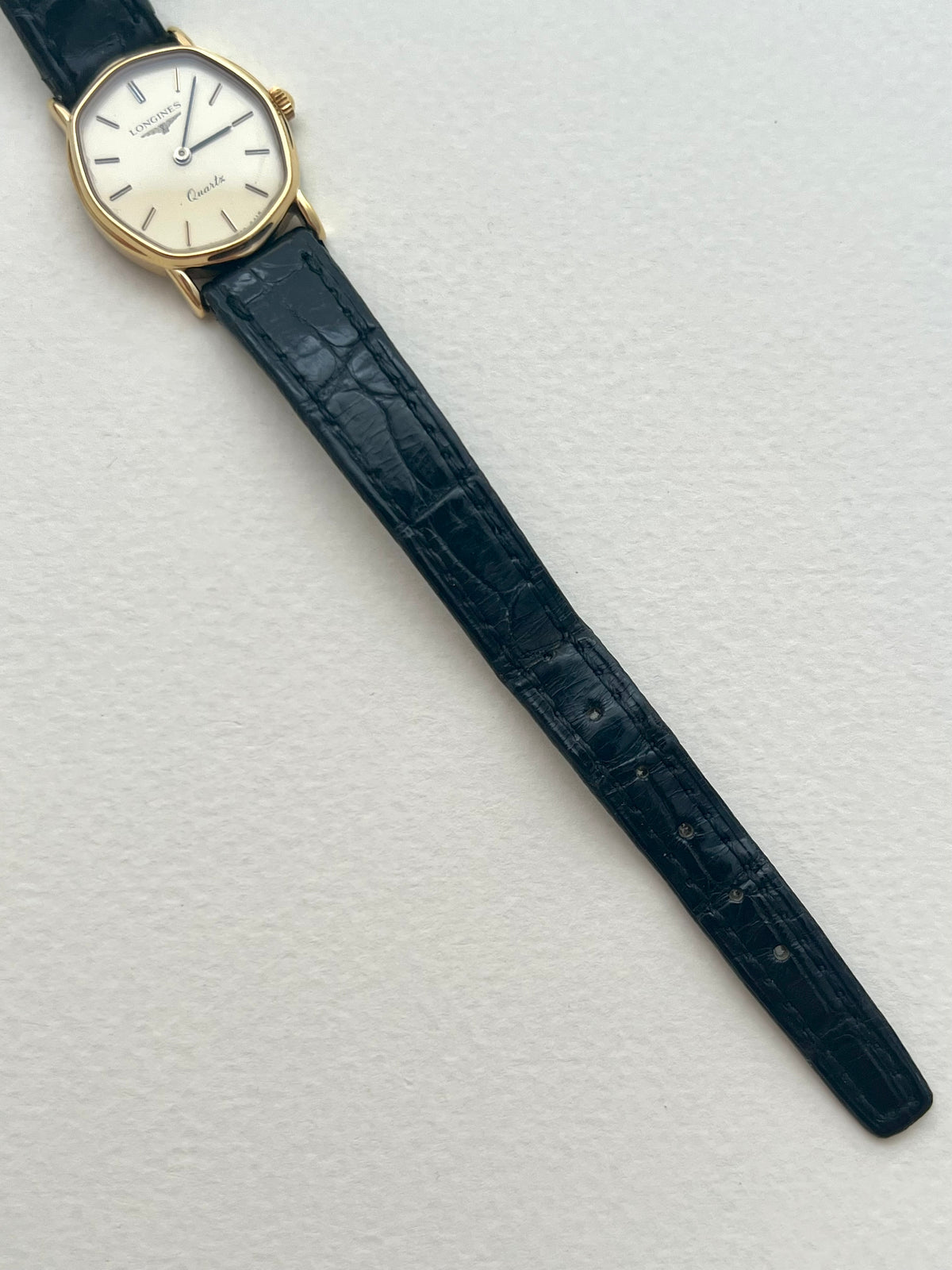 Detailed view of the cream Longines dial, gold-tone hour markers and blackened hands.