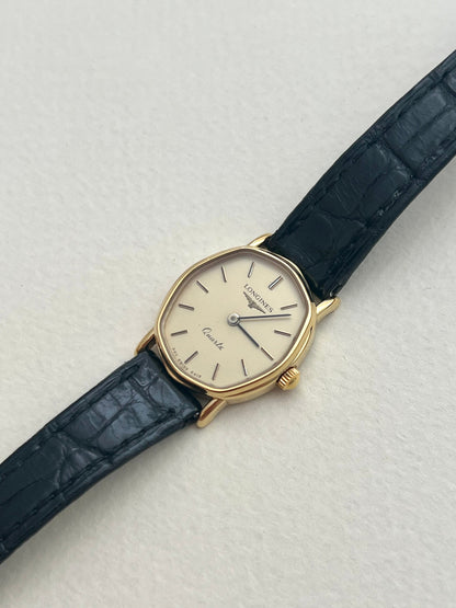 Longines gold-tone soft tonneau watch with original black leather strap worn on the wrist.