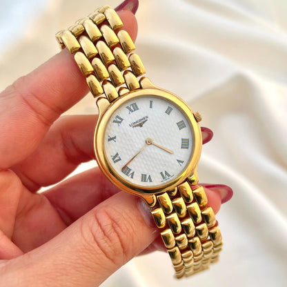 Longines women’s watch with textured white Roman numeral dial and gold tone sculptural bracelet