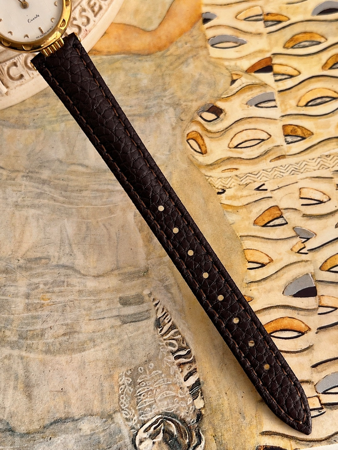 New aftermarket dark brown patterned leather strap with tonal stitching and adjustment holes.