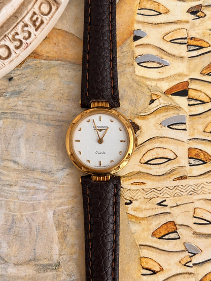 Front view of the Longines white patterned dial watch with gold tone crescent markers, decorated bezel and dark brown leather strap.