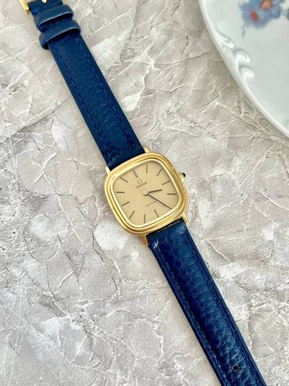 Omega De Ville square cushion watch with champagne dial, gold-tone case and navy blue textured strap