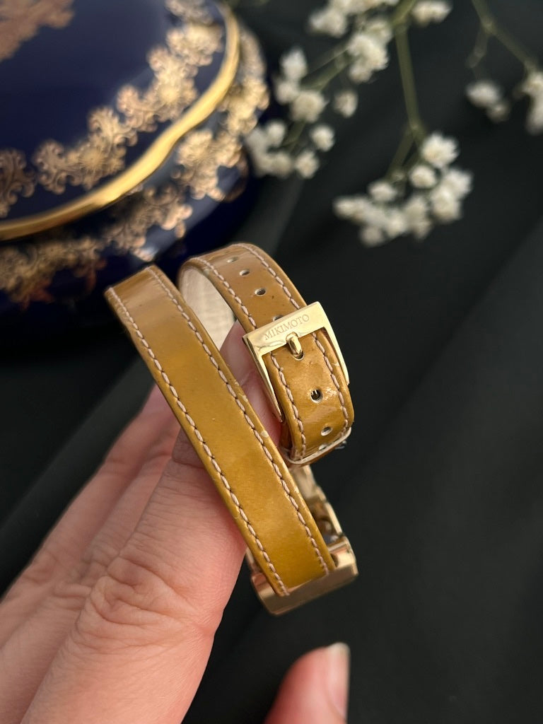 Original signed Mikimoto gold-tone buckle on tan embossed leather double-wrap strap