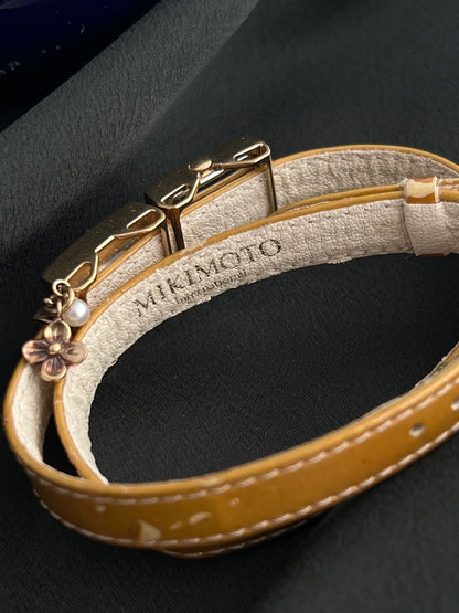 Mikimoto embossed leather strap interior with gold-tone floral charm and pearl accent