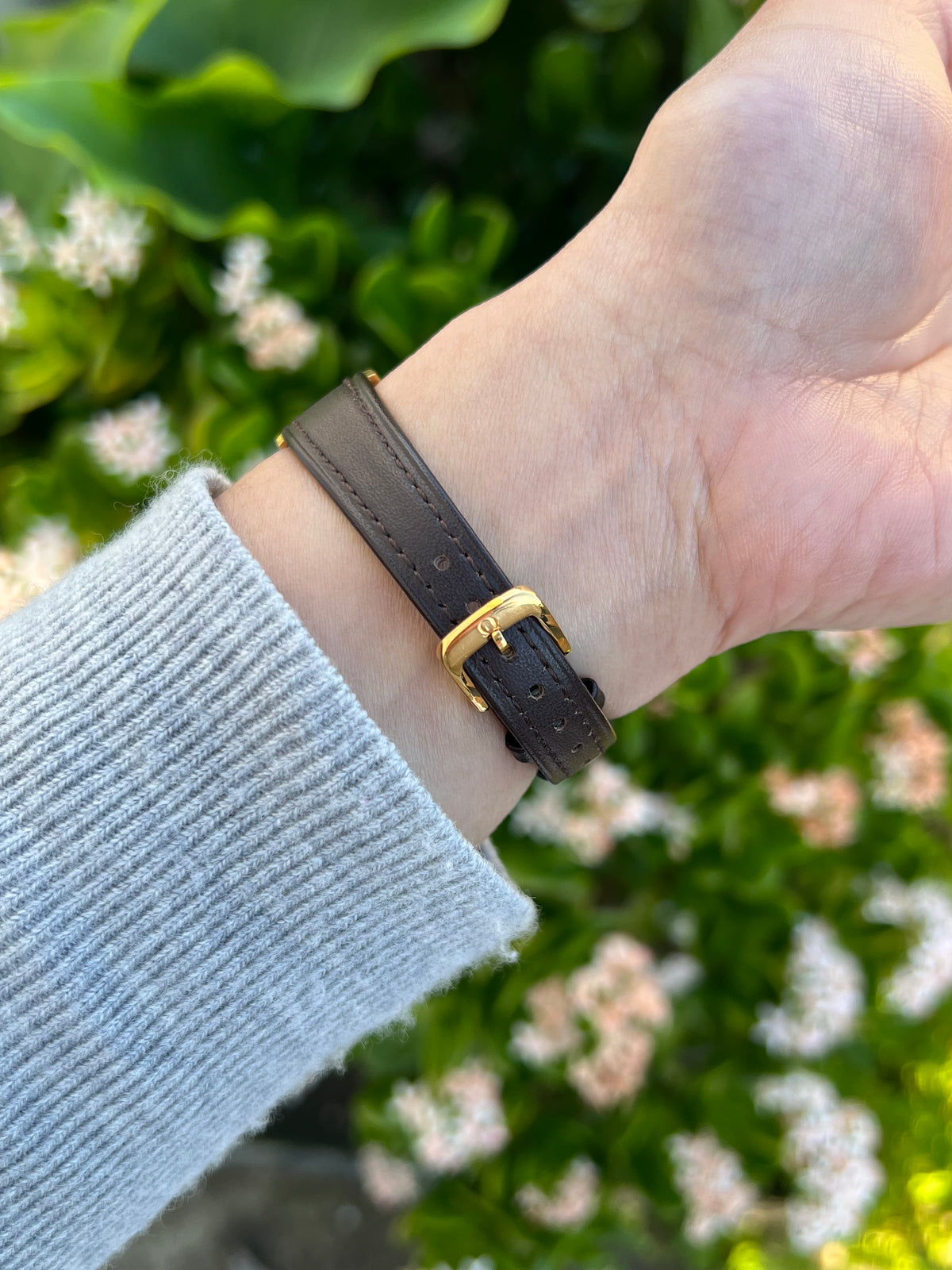 Close view of the dark leather strap and gold-tone buckle on the Omega Cushioned Gold Toned Woman's Watch.