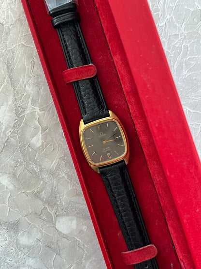 Omega De Ville 591.0099 with dark dial and black leather strap displayed in a red watch case