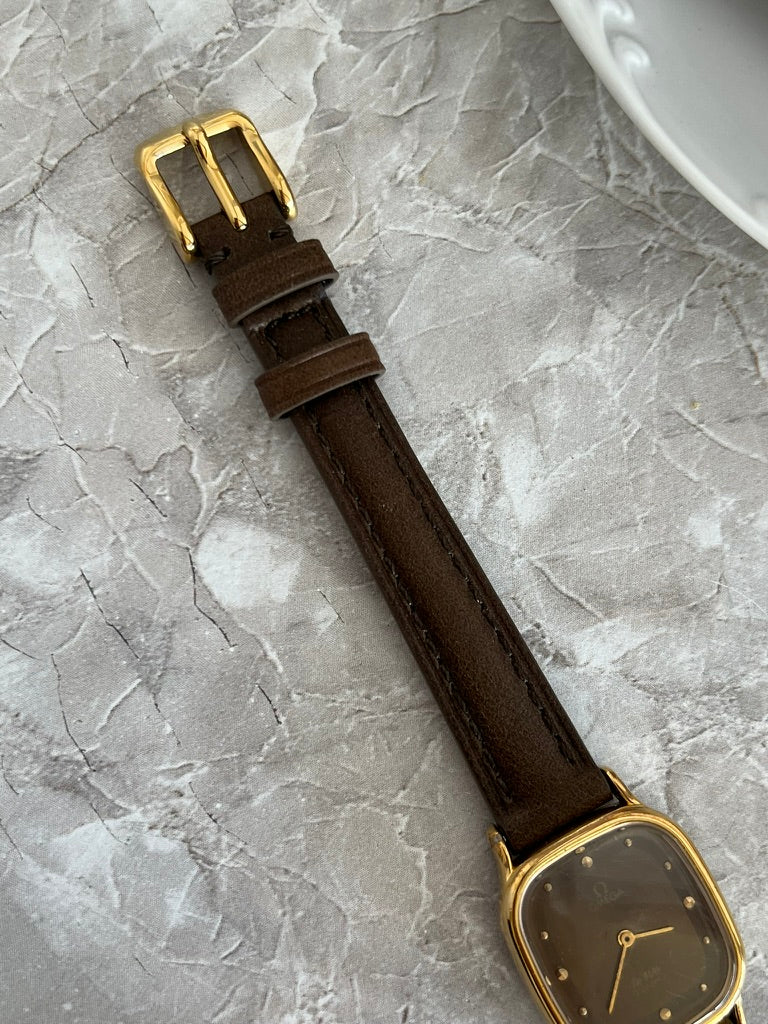 Brown strap and gold-tone pin buckle of Omega De Ville quartz watch