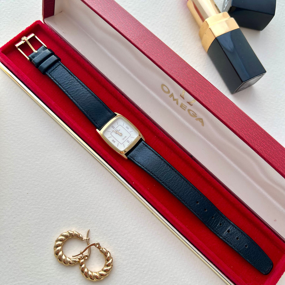 Front image of the Omega De Ville gold-tone rectangular watch with burgundy dial details.