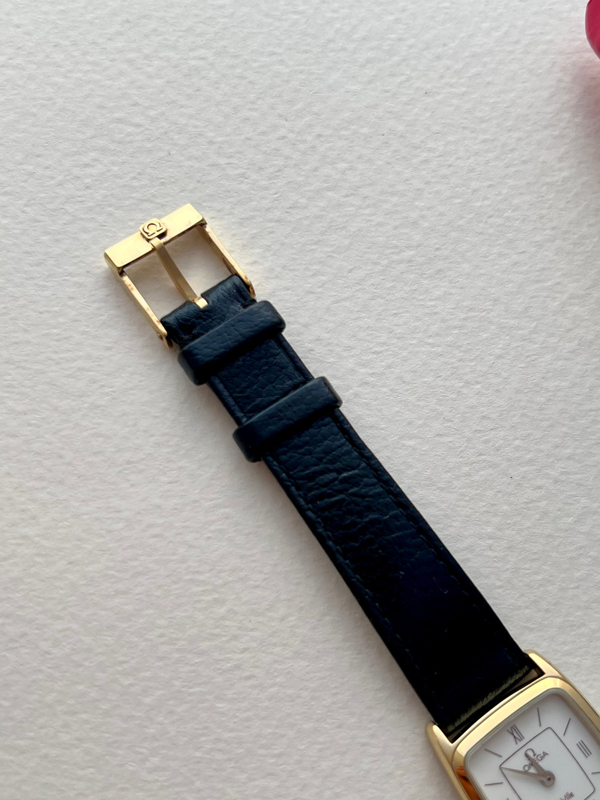 Angled detail of the gold-tone case and burgundy-accented dial.