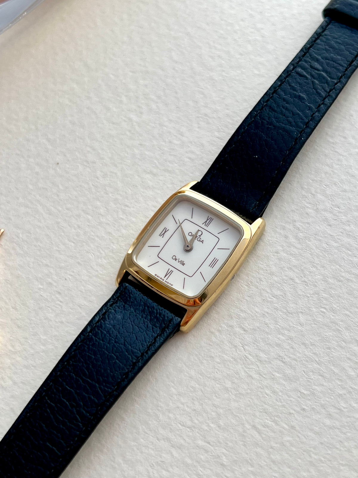 Front view highlighting the burgundy accents on the Omega De Ville dial.