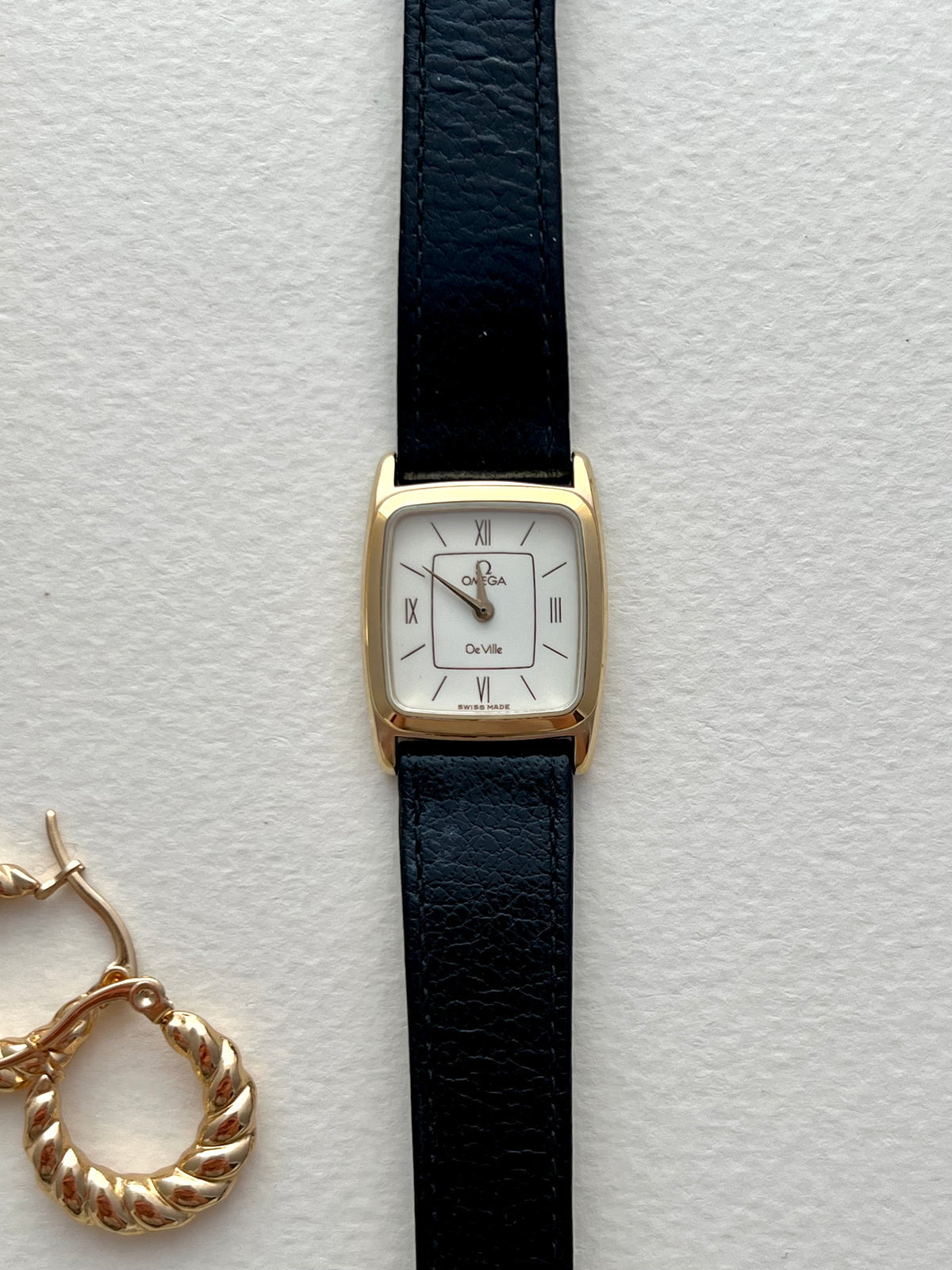 Omega De Ville gold-tone watch shown on a wrist.