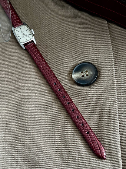 Full burgundy aftermarket leather strap and petite silver tone Omega De Ville on woven fabric