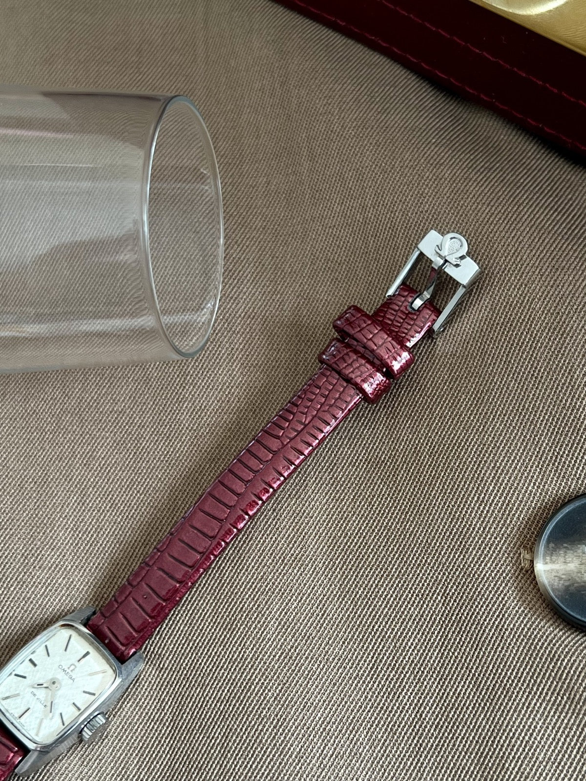 Burgundy embossed aftermarket leather strap with silver tone Omega signed buckle and two keepers