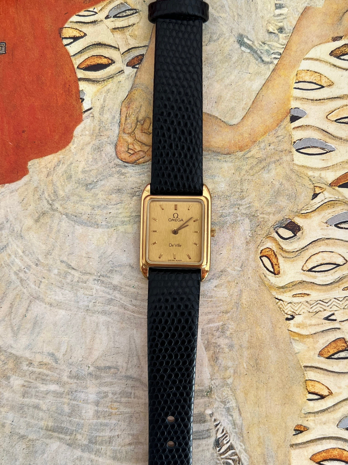 Straight-on view of the Omega De Ville champagne dial, applied gold tone baton markers, two hands and curved gold tone lugs.