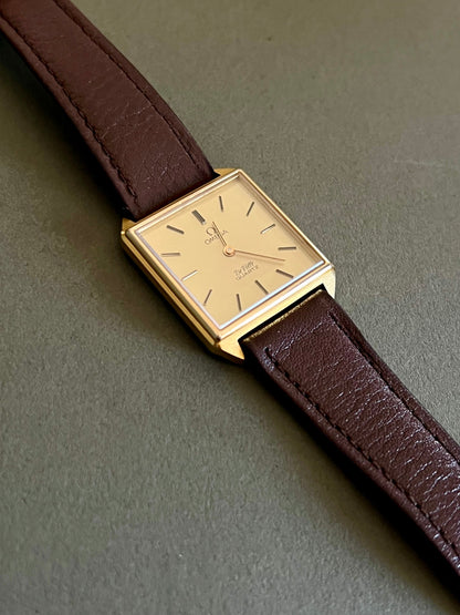 Vintage Omega De Ville square gold-tone watch with champagne dial and brown leather strap.