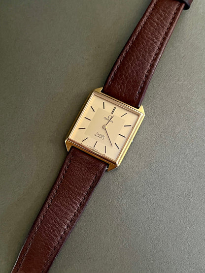 Vintage Omega De Ville watch with gold-tone case, champagne dial and brown leather strap.