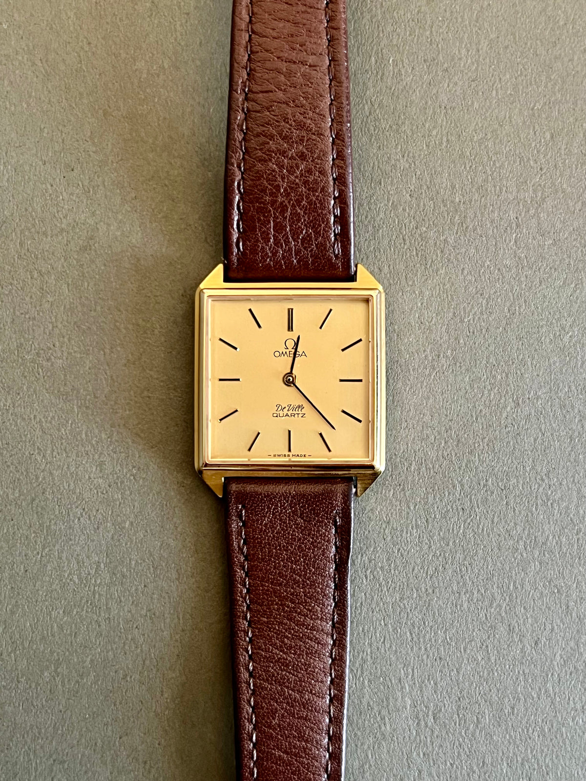 Brown aftermarket leather strap and gold-tone Omega buckle for the De Ville watch.