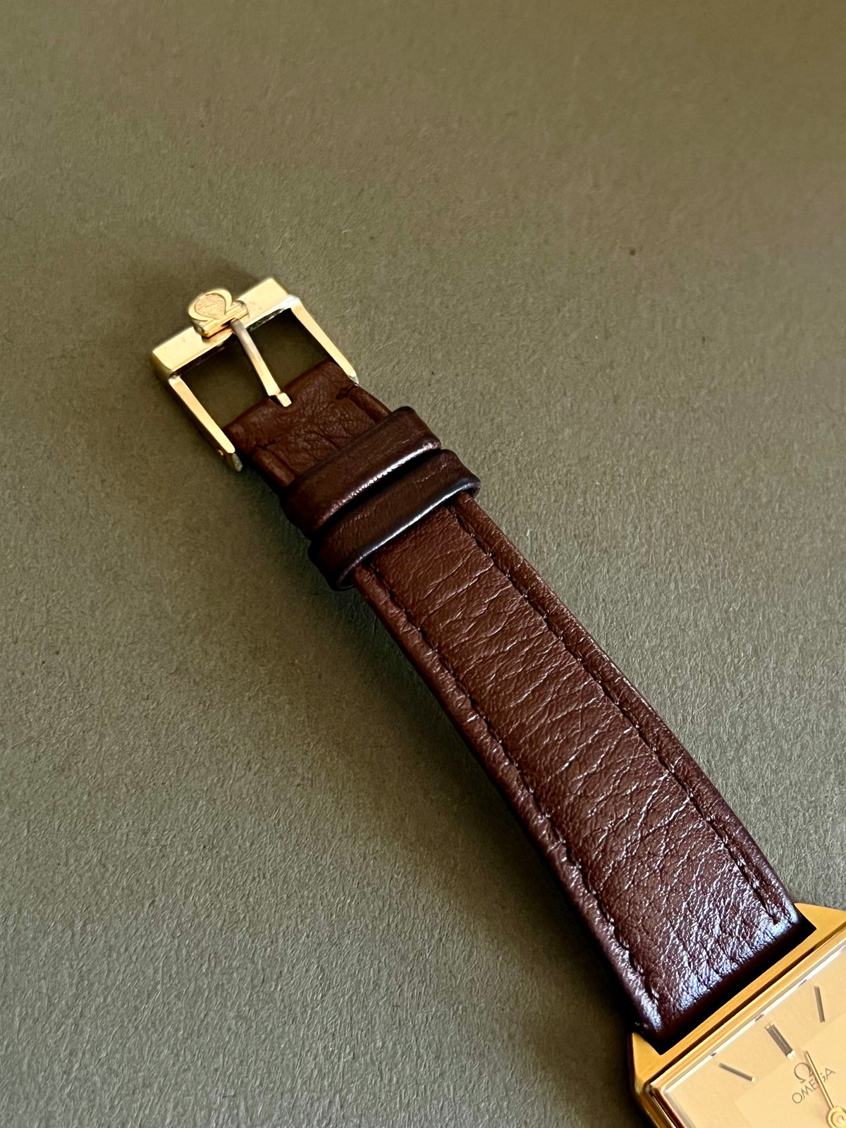 Champagne dial and double-frame rectangular case of the Omega De Ville watch.