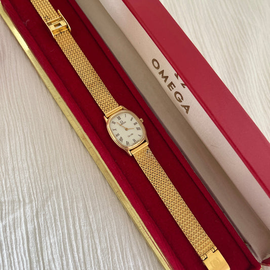 Omega De Ville gold mesh watch shown with its box.