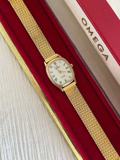 Close-up of the champagne dial with burgundy Roman numerals on the Omega De Ville.