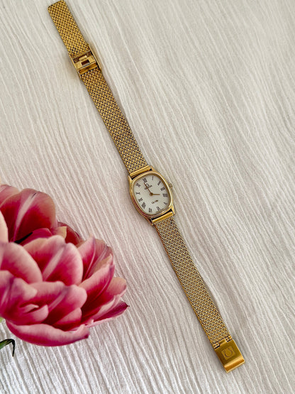 Omega De Ville champagne dial watch shown on a wrist.